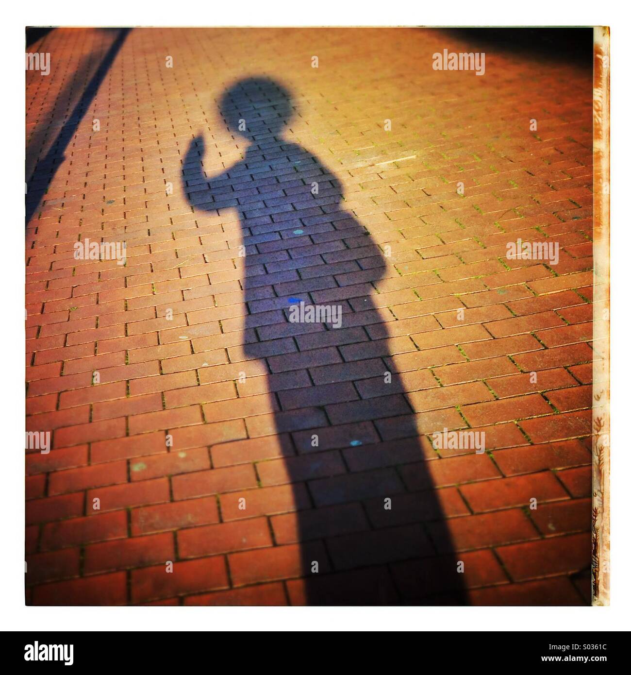 Shadow of a woman on pavement sidewalk - Smartphone Captured Stock Image