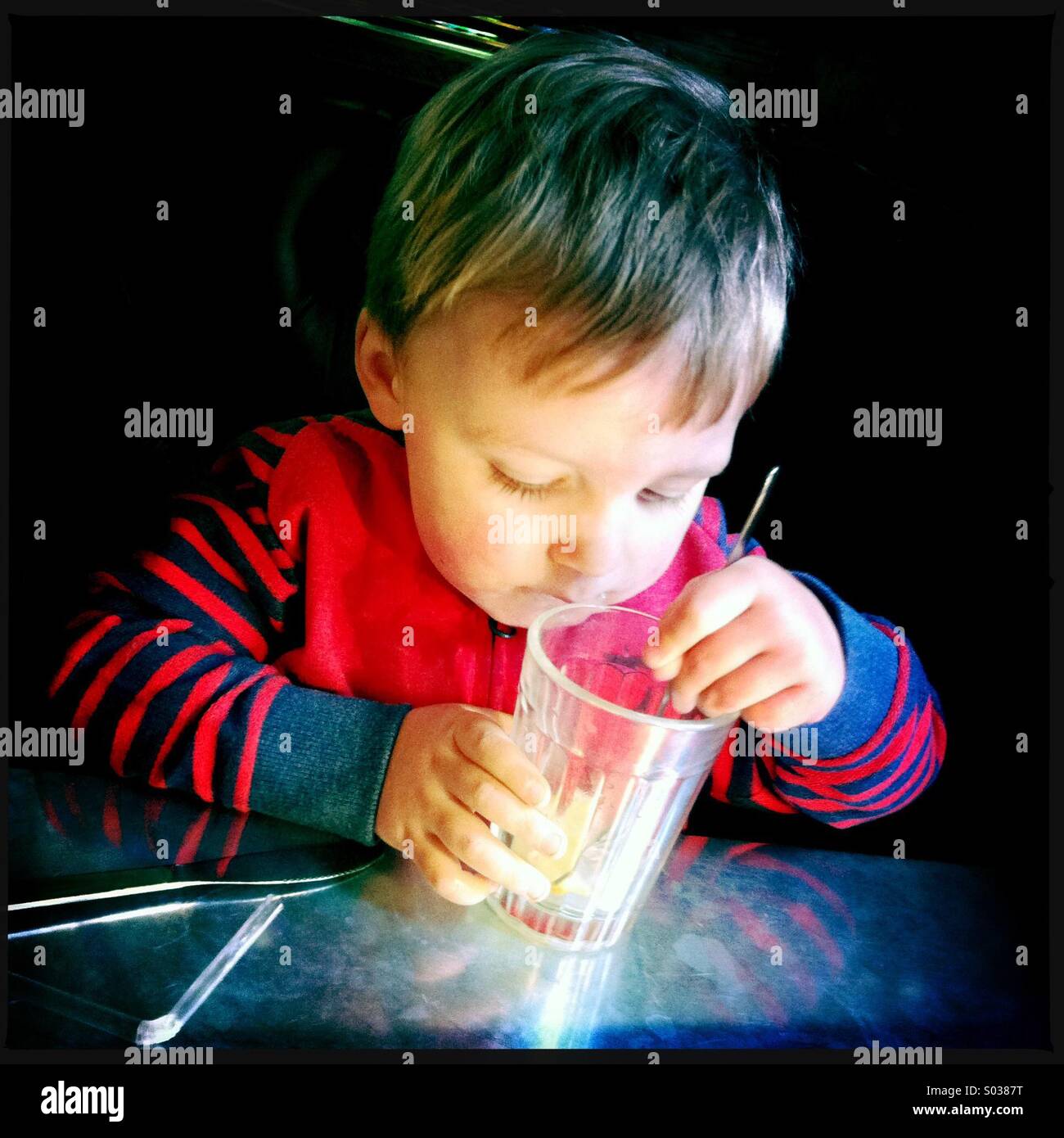 Young boy looking closely at what he has left to drink Stock Photo