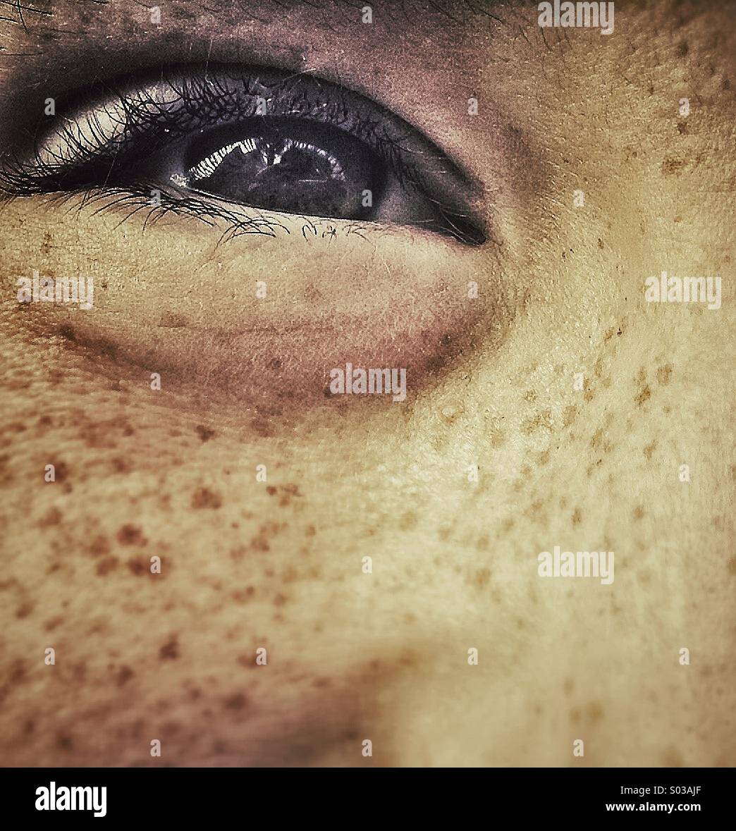 Freckled eye smiling. Close up half face of young cheeky boy smiling. Stock Photo