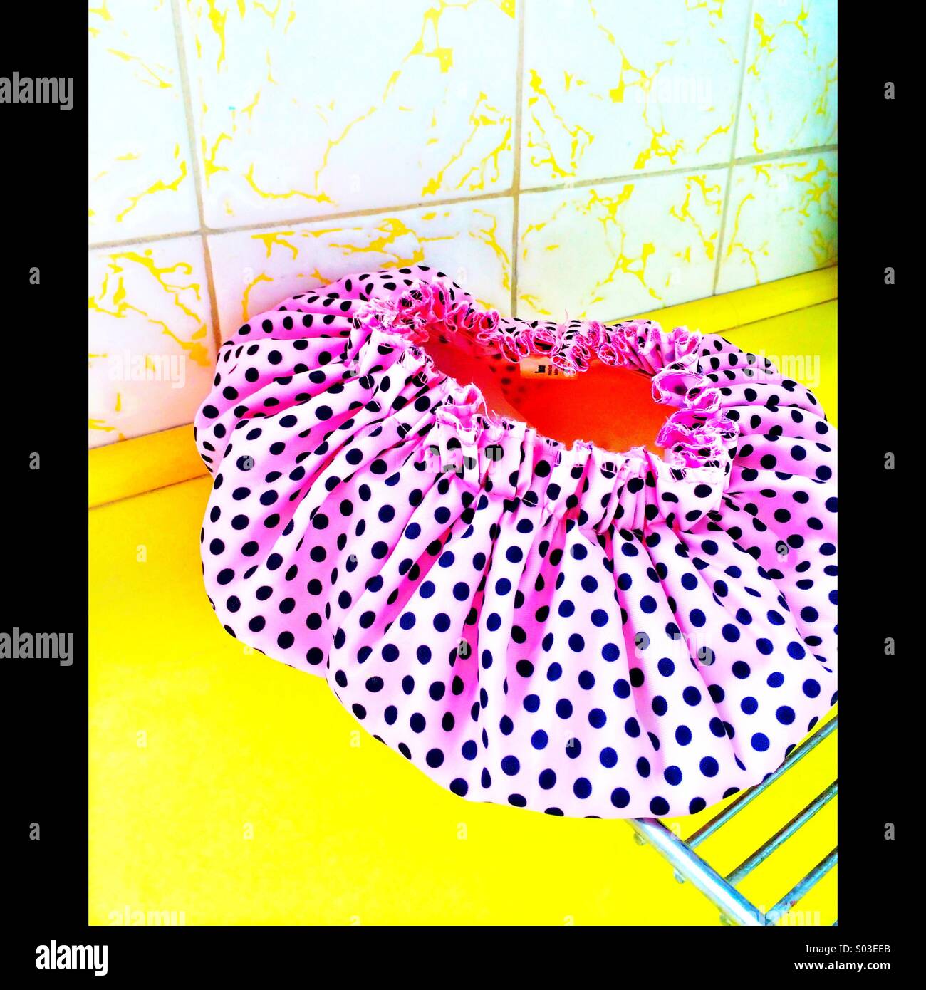 Pink spotted shower cap in retro 1970's yellow bathroom Stock Photo