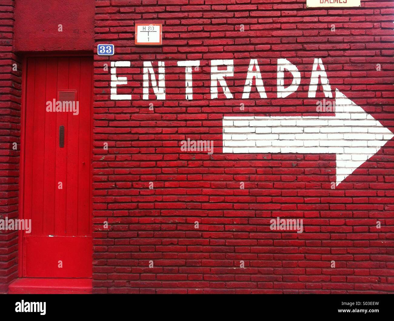 White Direction Arrow Sign And Entry Word Written In Spanish On A