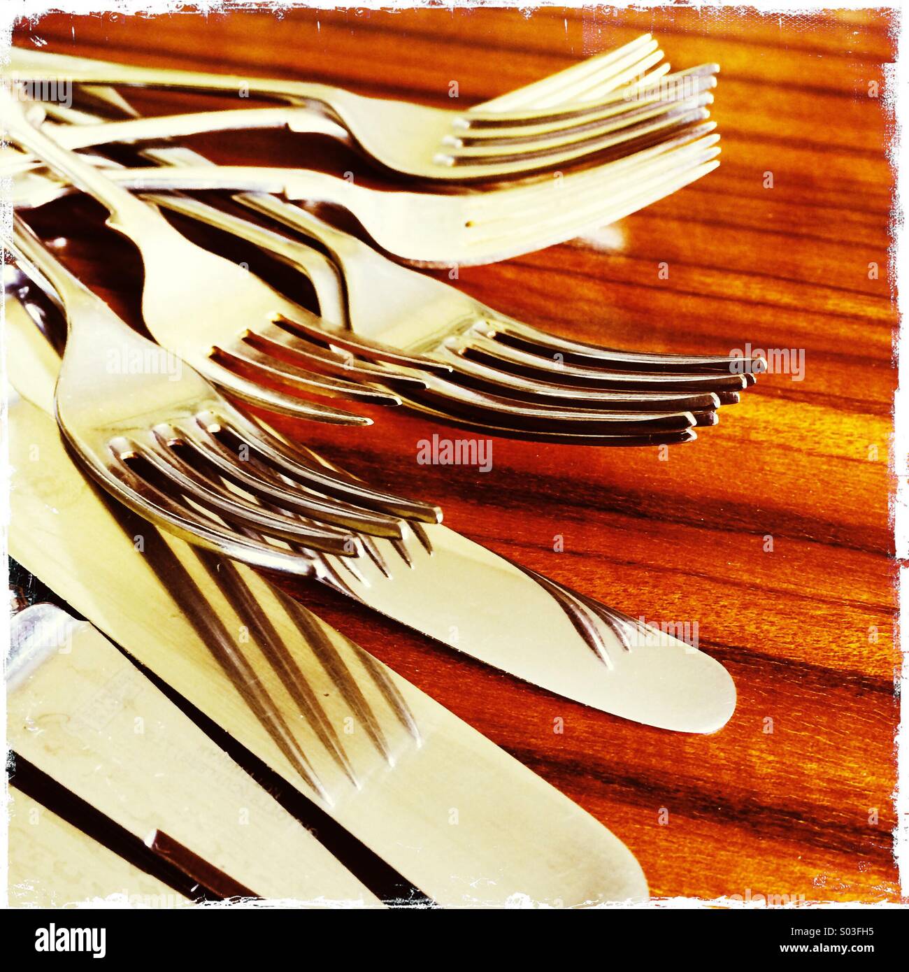 Cutlery with reflections on 1960's polished wood grain dining table - Smartphone Captured Stock Image