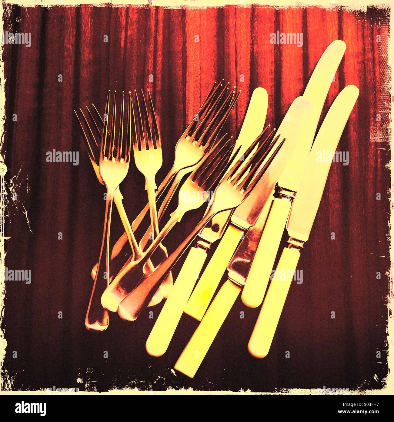 Pile of knives and forks on 1960's retro polished dining table - Smartphone Captured Stock Image