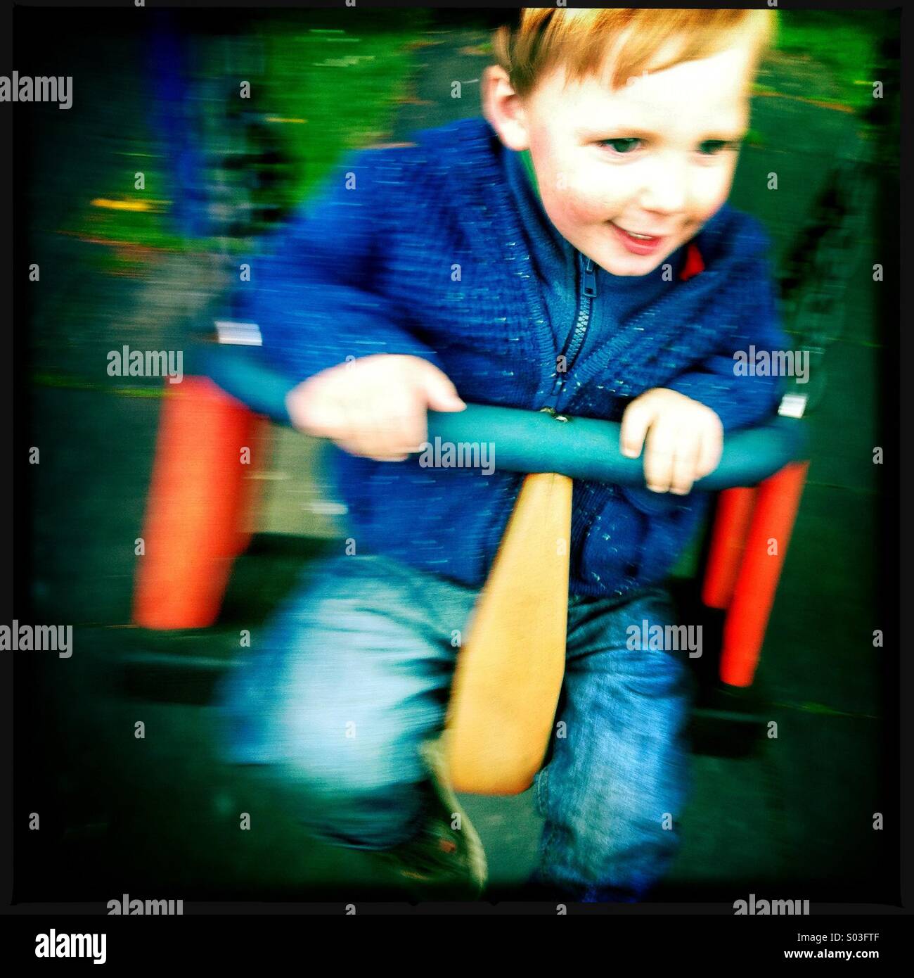 A young boy having fun on a swing at the play park Stock Photo