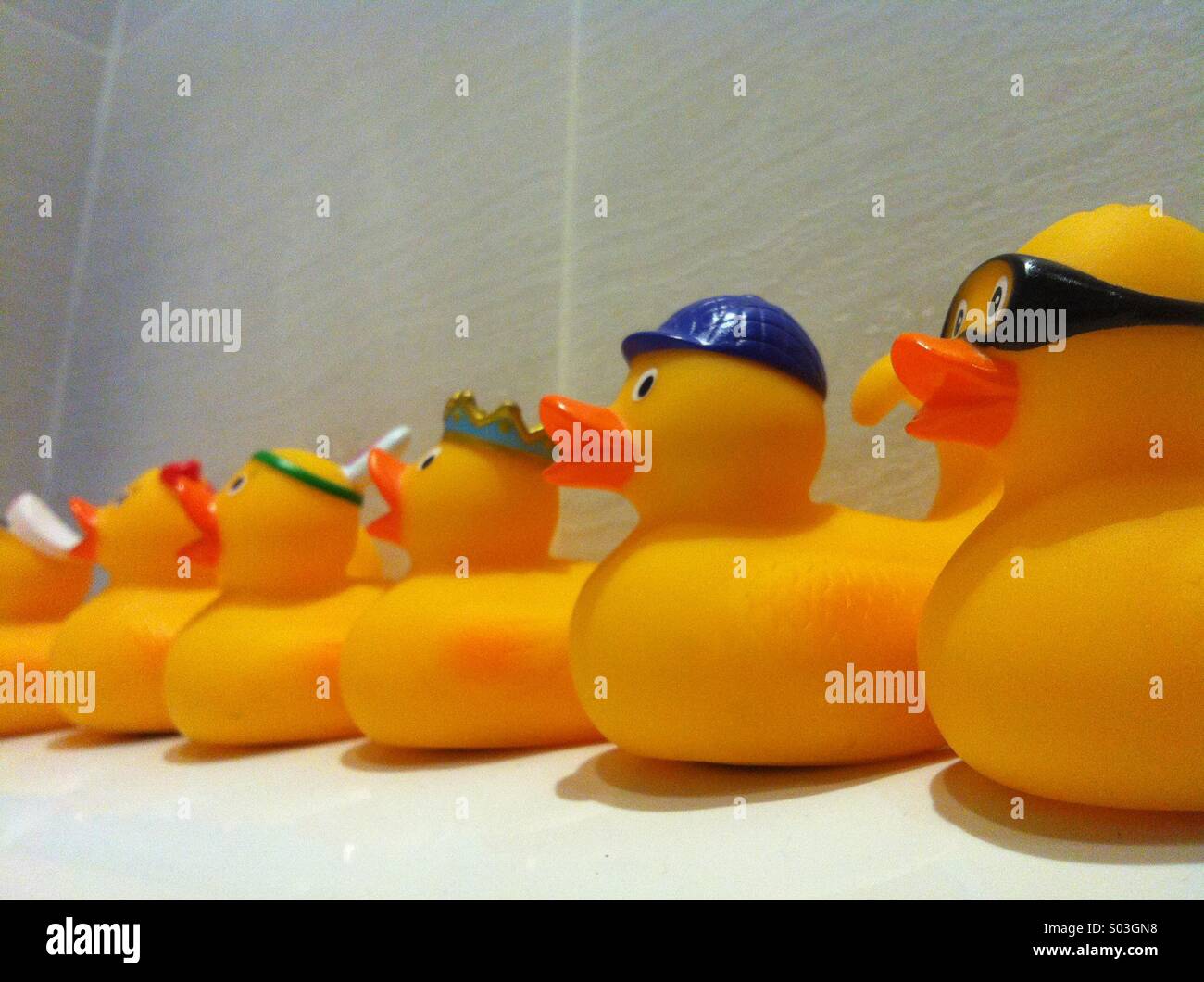 Different yellow bath ducks lined up in a row Stock Photo