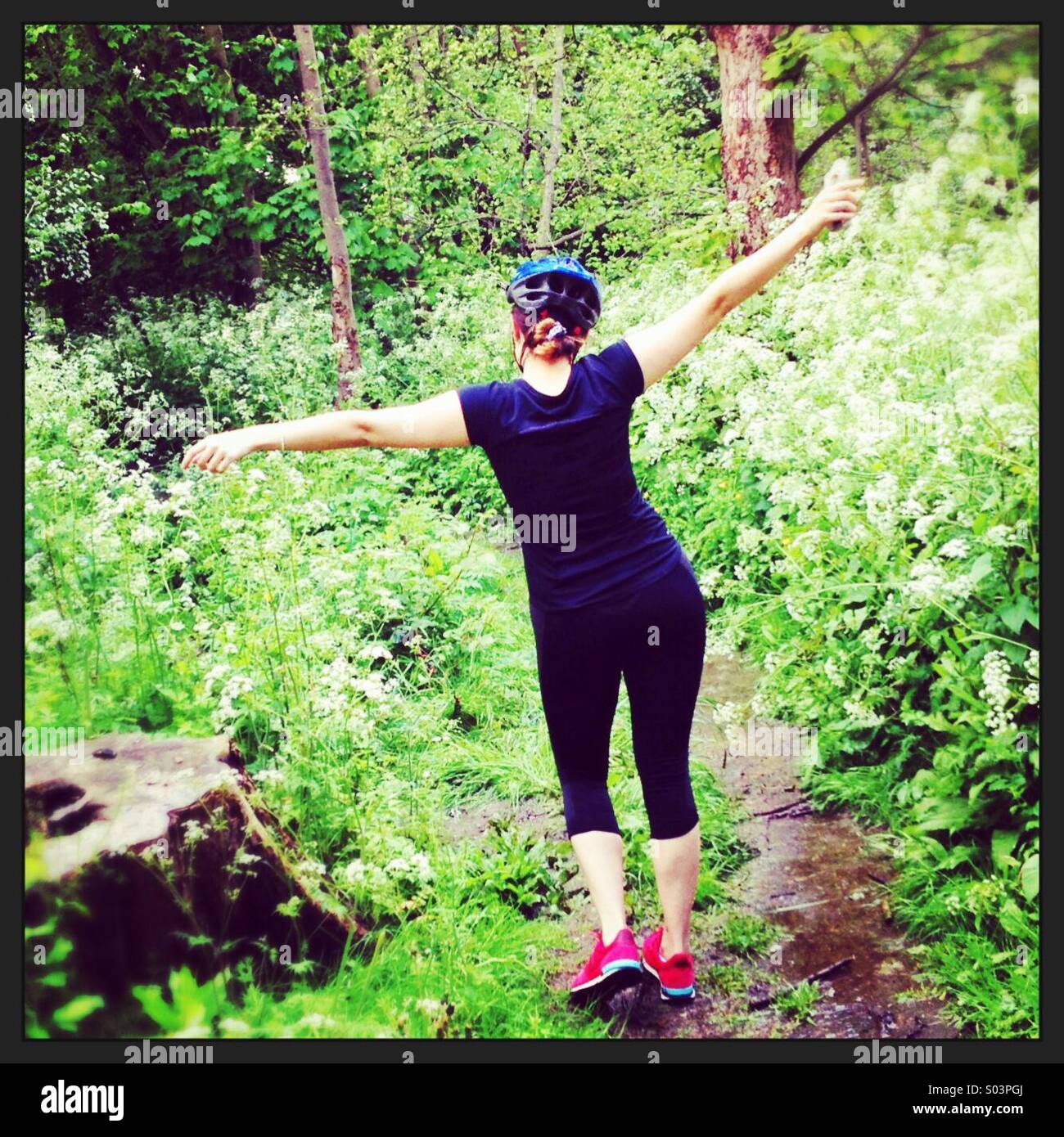 Young female wearing cycling gear, waving her arms in the air, enjoying the countryside. - Smartphone Captured Stock Image