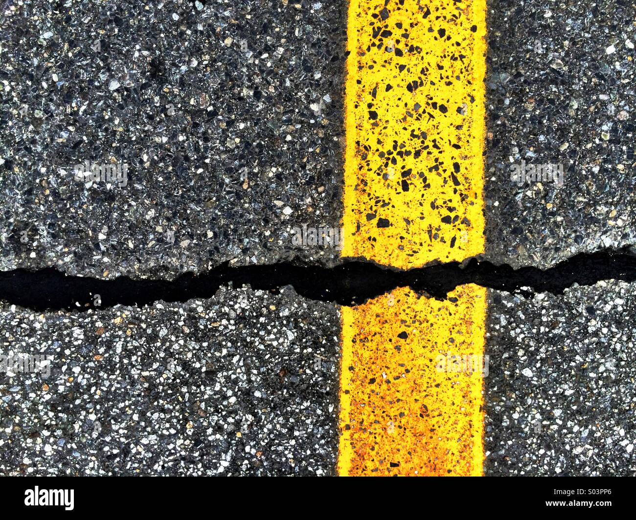Yellow line and black tar on pavement, with texture and strong geometry. Stock Photo