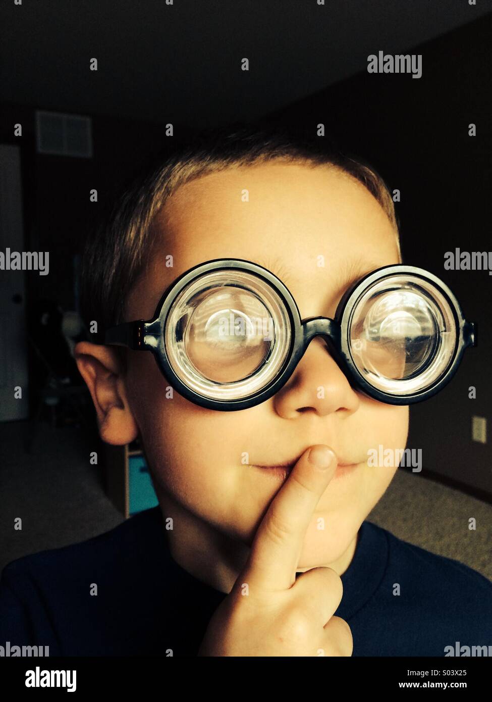 A young boy wearing large glasses contemplates. Stock Photo
