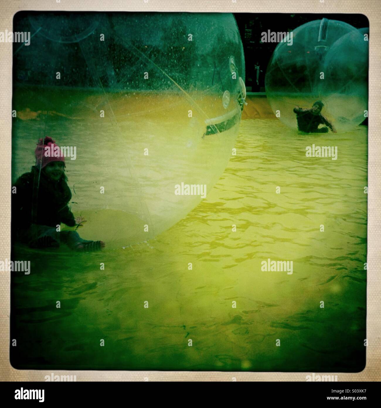 Two children playing in water balloons. - Smartphone Captured Stock Image