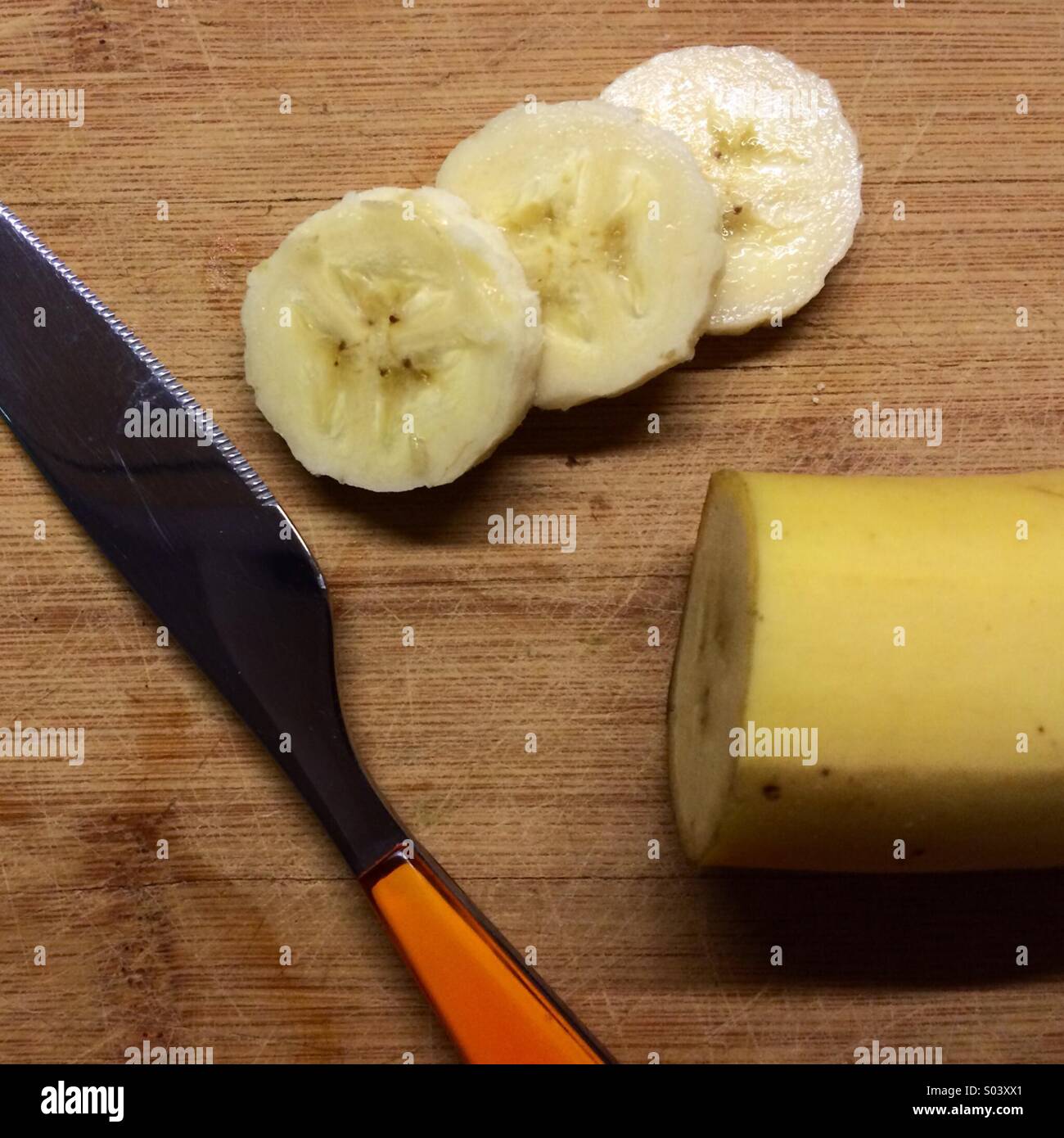 Sliced banana with orange knife Stock Photo