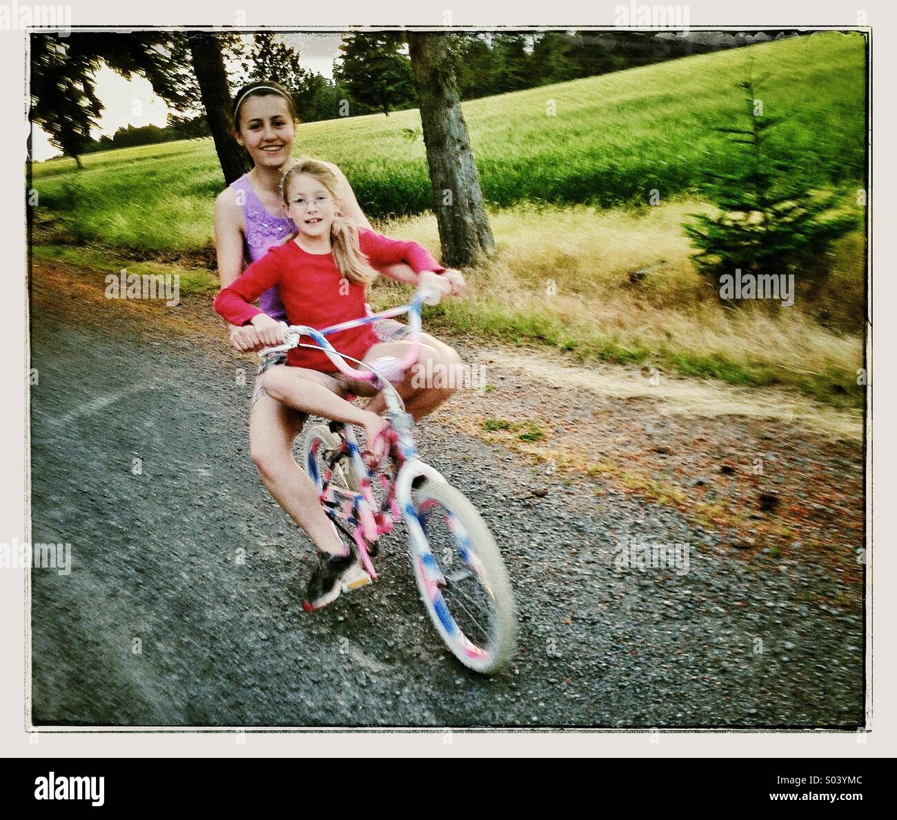 Two young girls riding bike together Stock Photo
