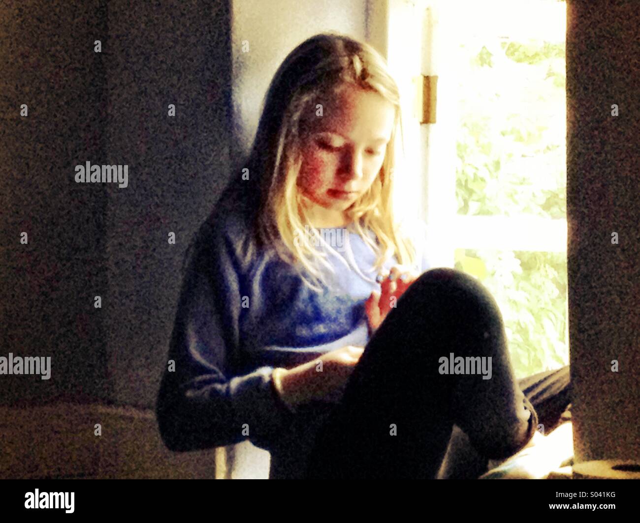 Girl reading in window light - Smartphone Captured Stock Image