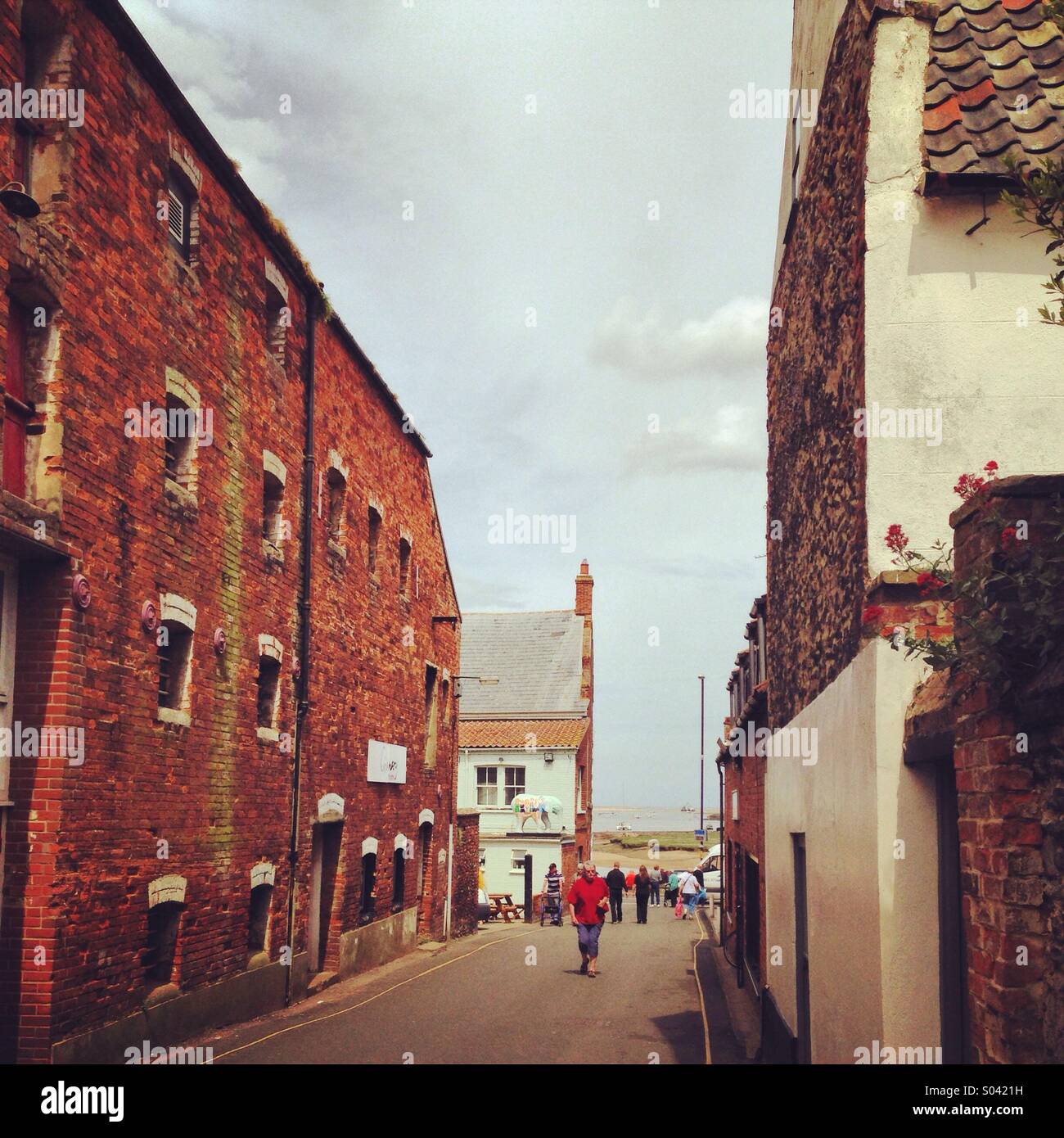 Wells-next-the-Sea Norfolk. Holiday makers stroll up Staithe Street. Stock Photo