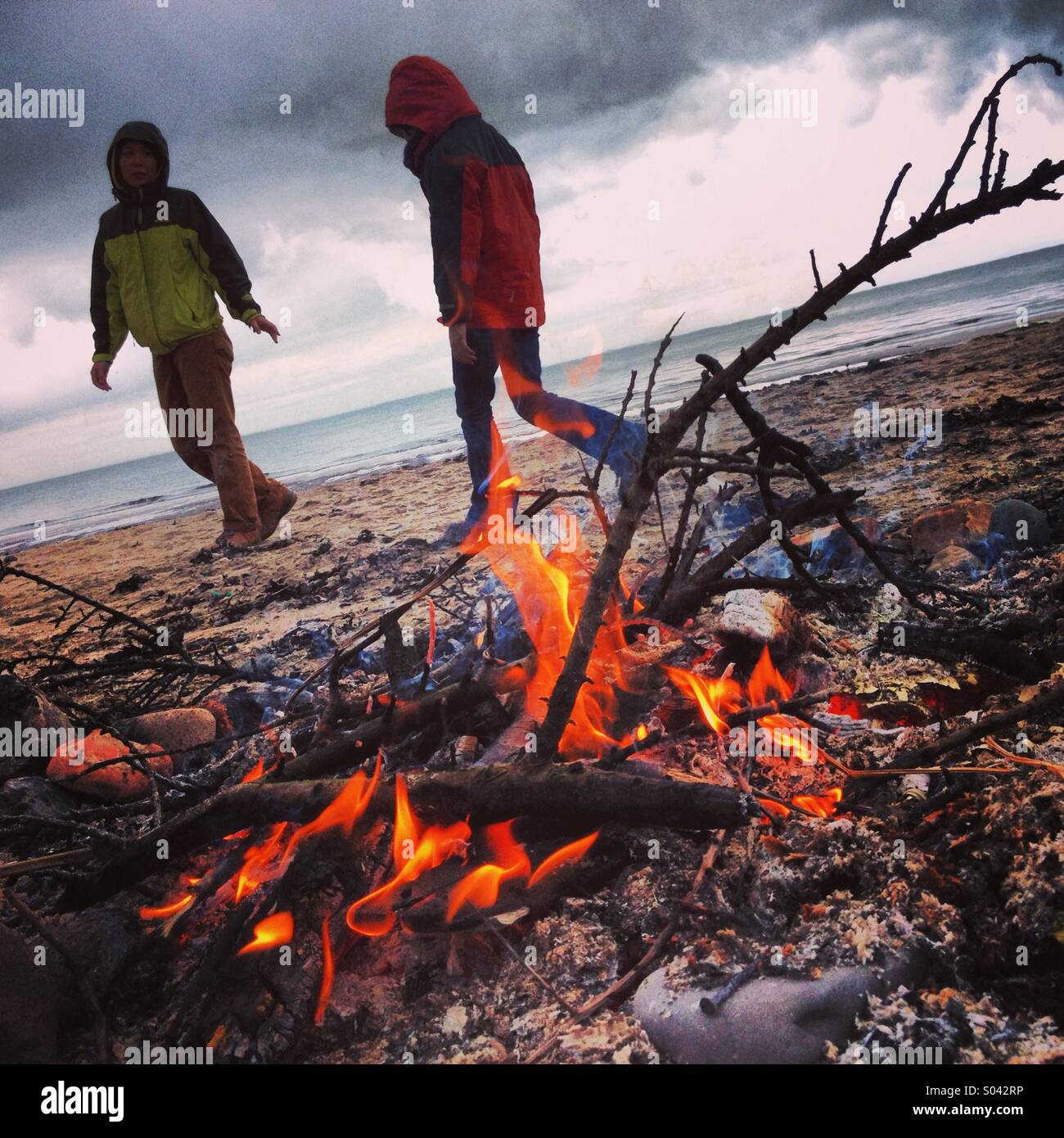 Camp fire on beach, with parent and child. Scotland. Stock Photo