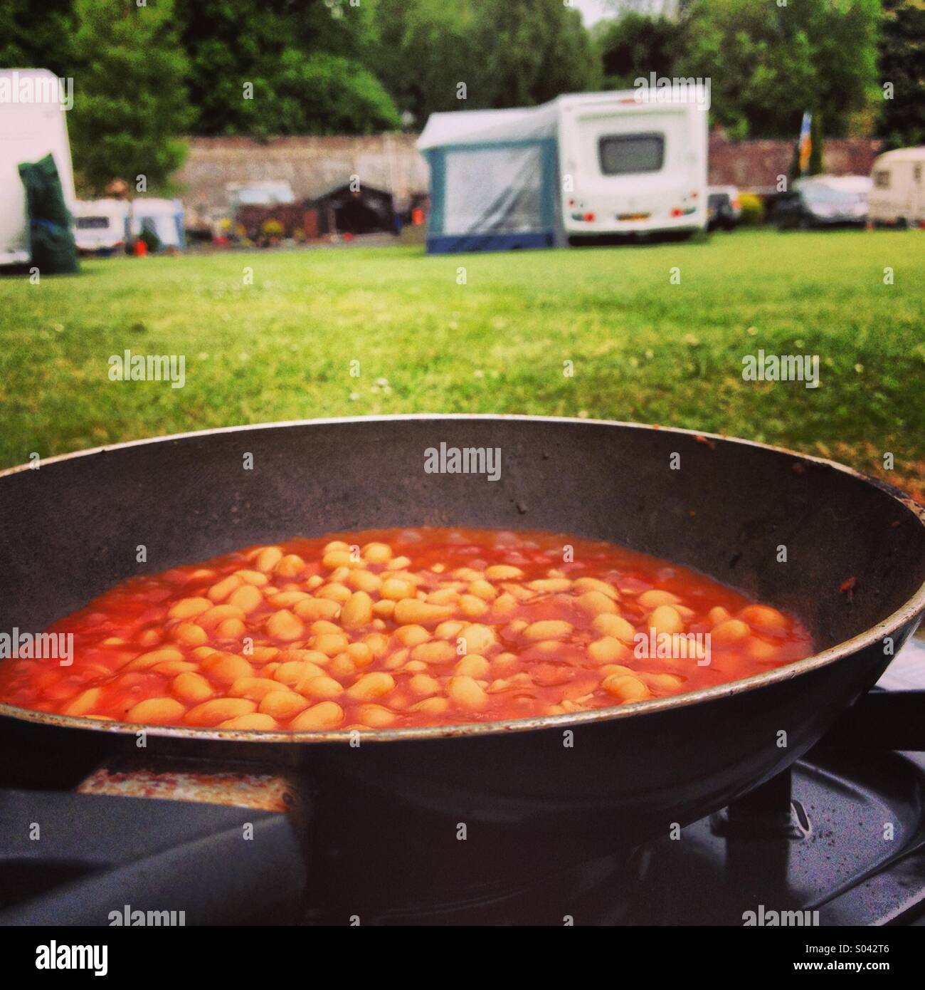 Bsked beans cooking on outdoor stove in camp site. Stock Photo