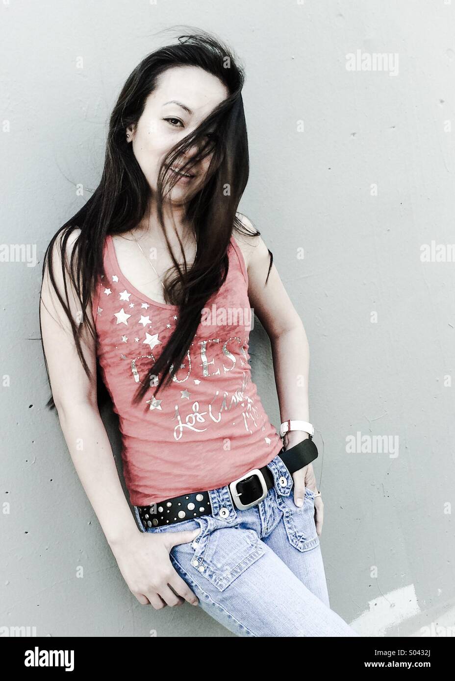 Asian girl leaning against a wall in a 3/4 pose Stock Photo - Alamy