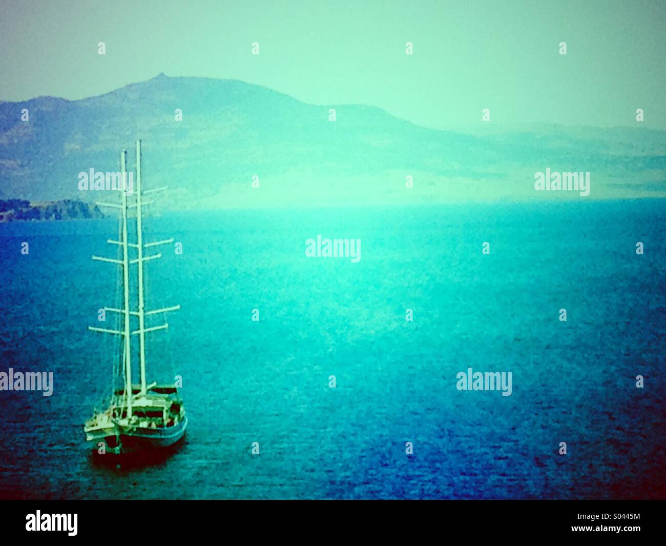 Sailboat moored off the coast of a Greek island - Smartphone Captured Stock Image