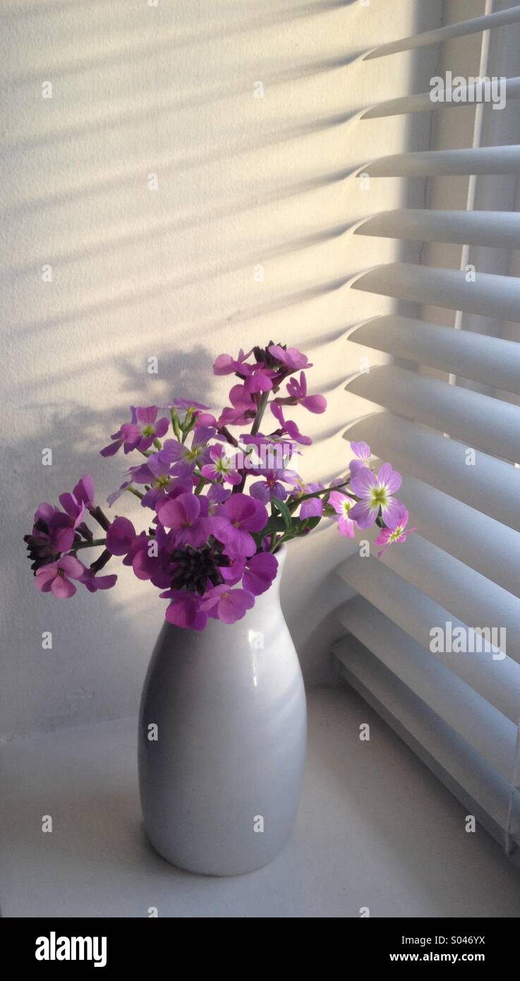 Small vase of flowers on windowsill Stock Photo