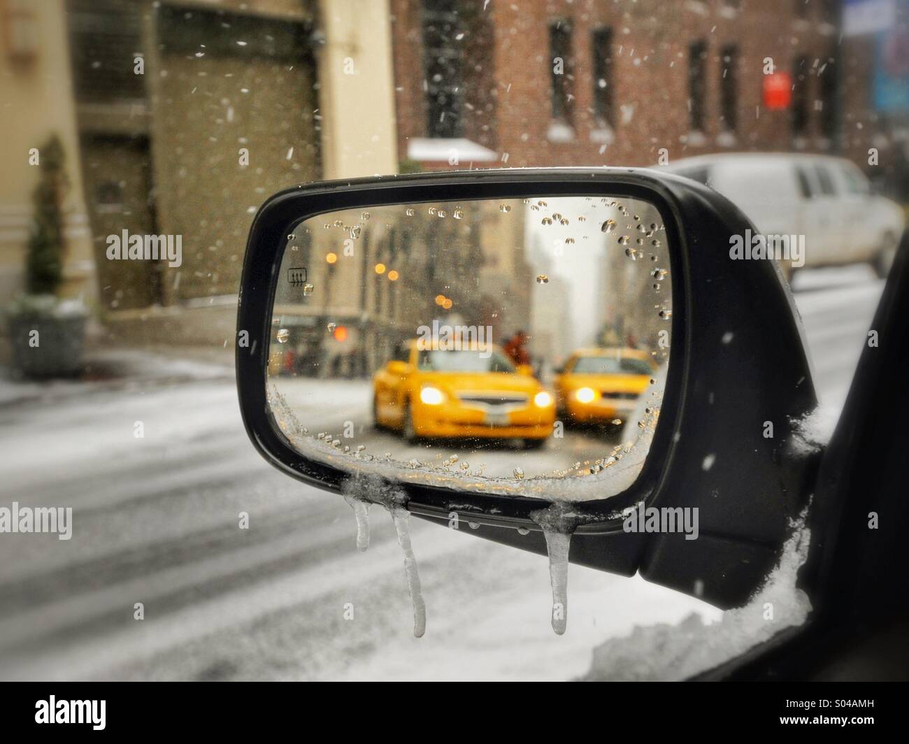 Looking into car rearview mirror at taxicabs on New York City Street on snowy day - Smartphone Captured Stock Image