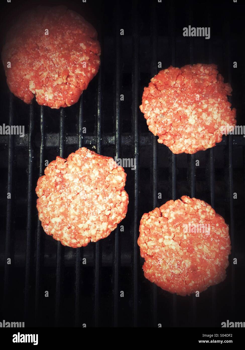 Four hamburger patties cooking on a gas grill Stock Photo Alamy