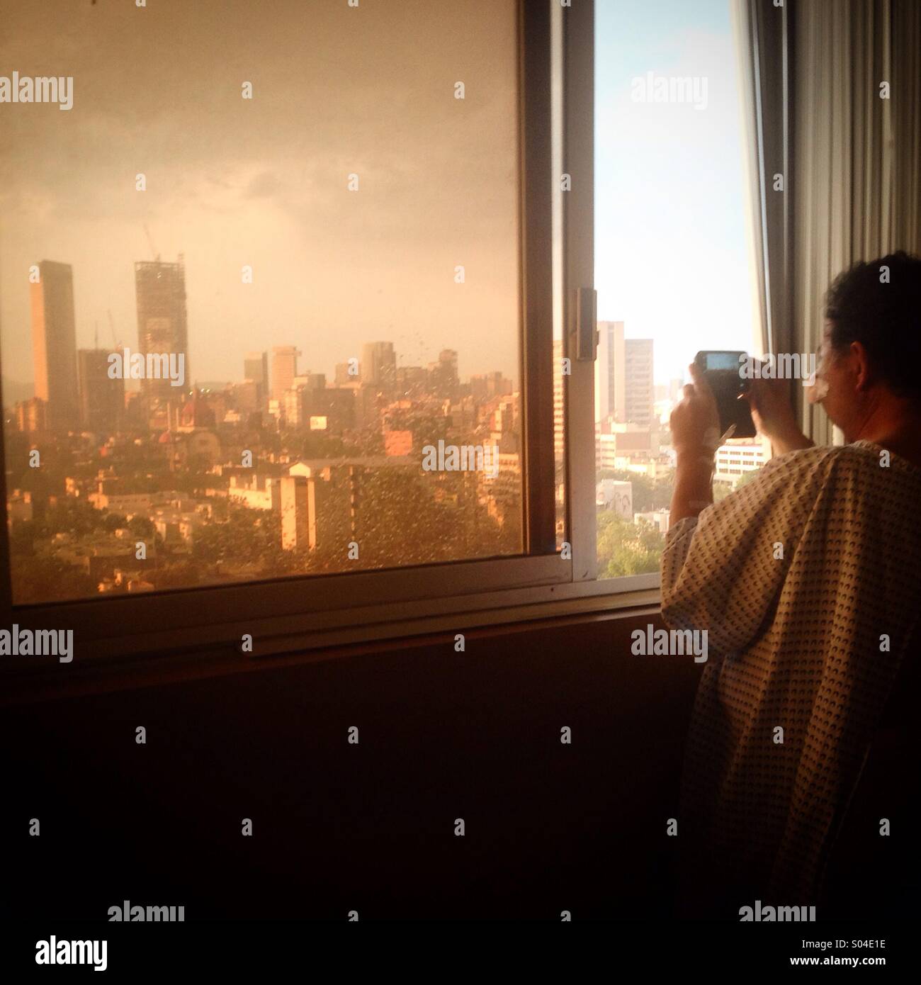 Chilean photographer Marco Ugarte takes a picture of Mexico City from his room in Hospital Mocel while he waits for a surgery in his nose. Marco was attacked by a protester during a protest. - Smartphone Captured Stock Image