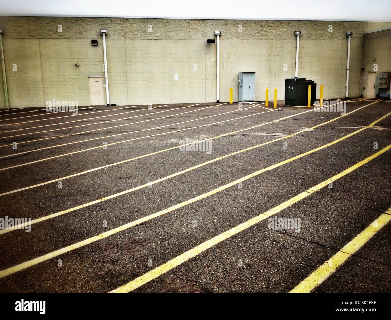 Asphalt parking area with yellow stripes in back of building Stock Photo