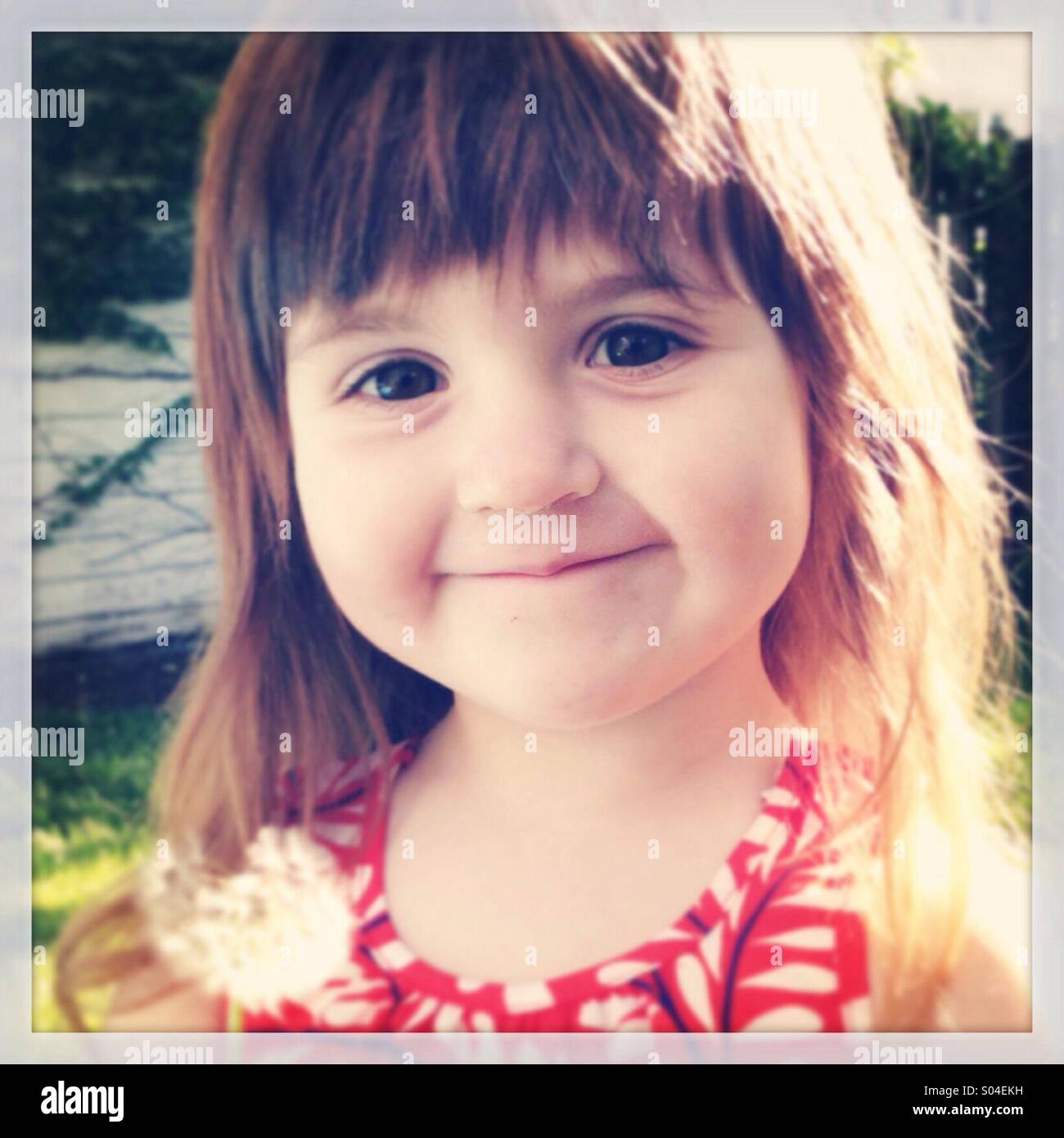 Smiling Caucasian girl with flower in sunlight - Smartphone Captured Stock Image