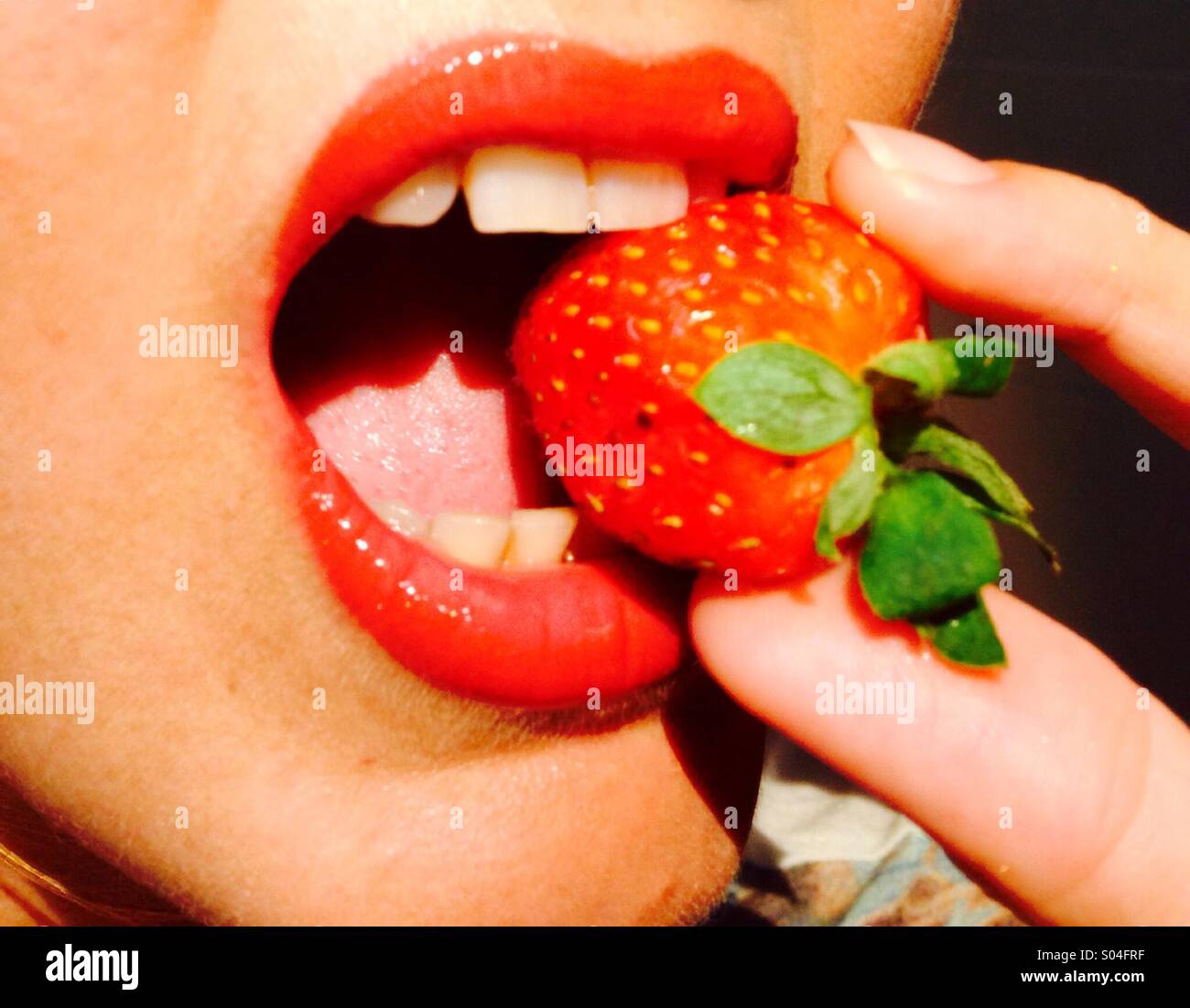 Strawberry being bitten between red lips - Smartphone Captured Stock Image
