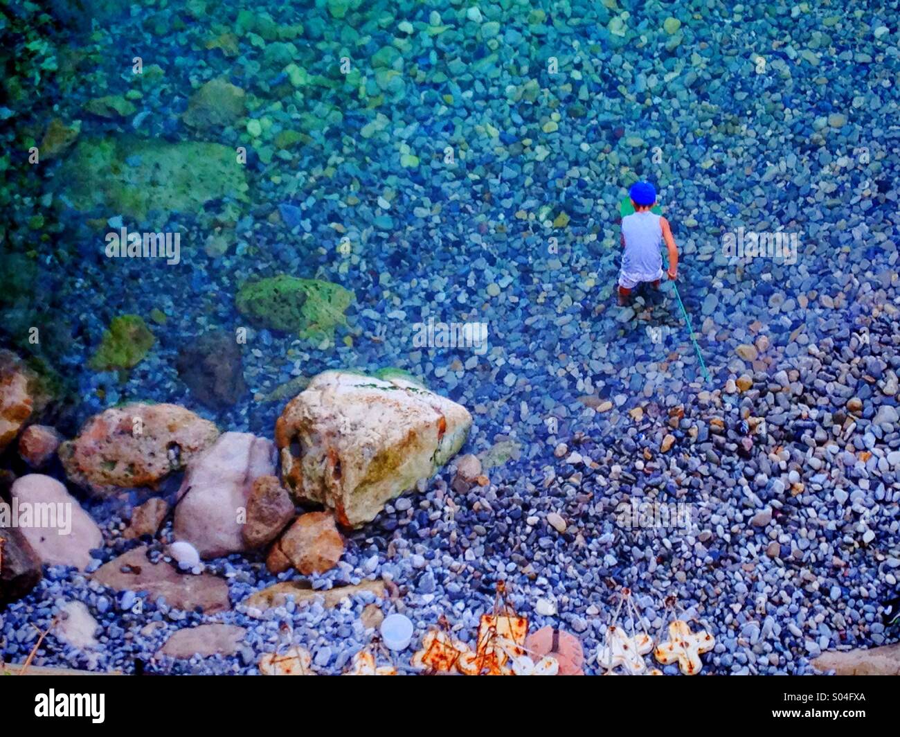 Man in the water on a rocky beach - Smartphone Captured Stock Image