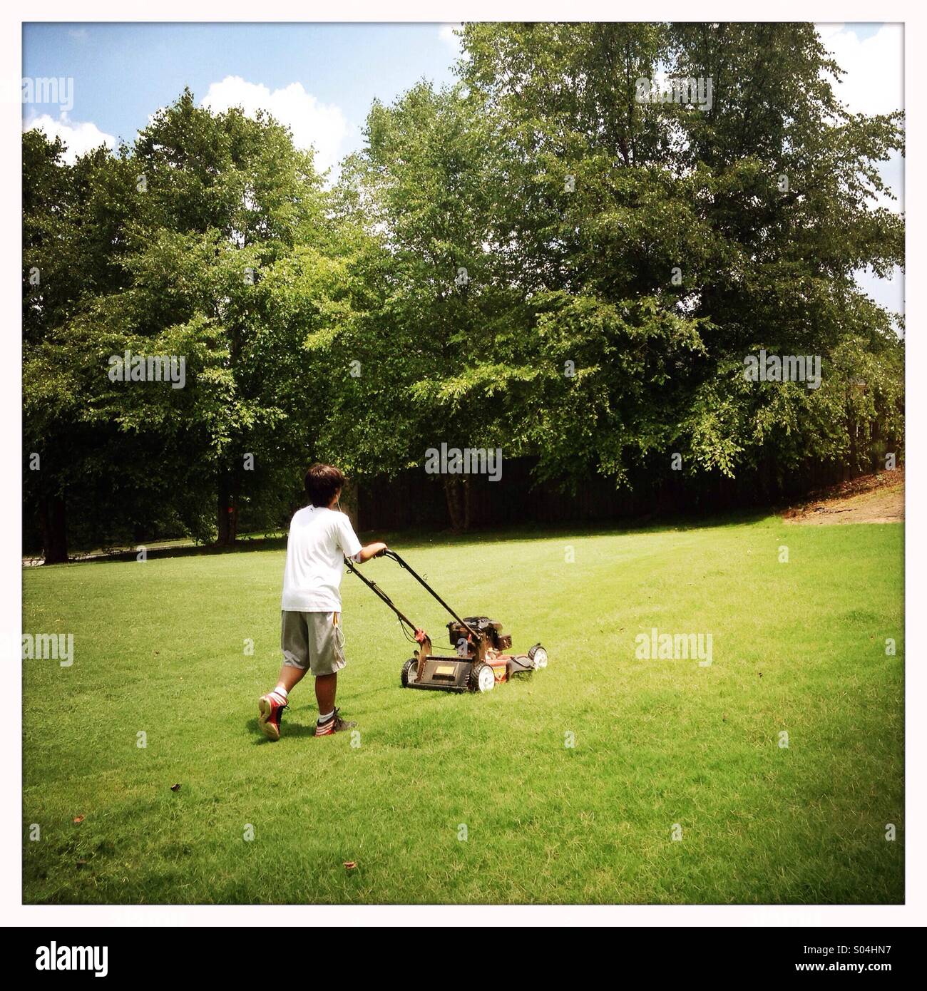 Boy mowing lawn Stock Photo