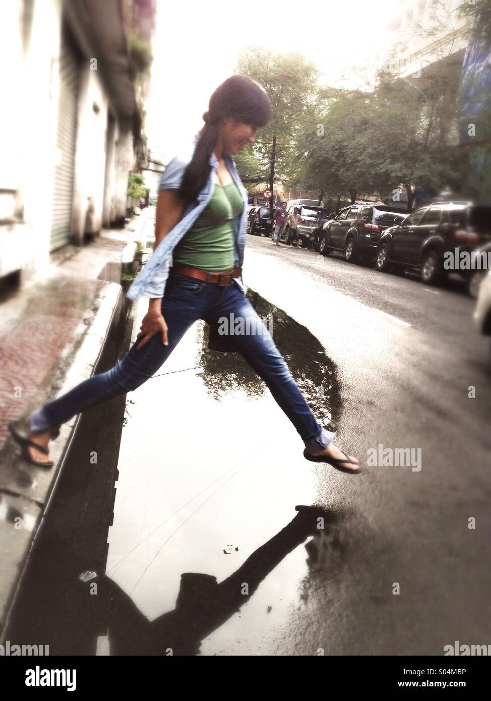 Asian girl stepping over puddle in Saigon hcmc Vietnam Stock Photo
