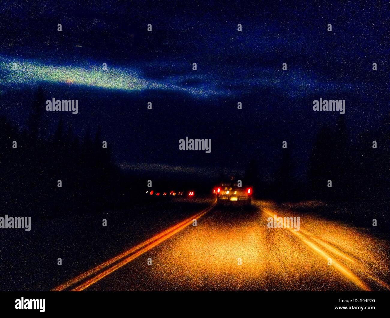 Glowing taillights of cars on a highway at night as the last of the light fades from the sky. Stock Photo