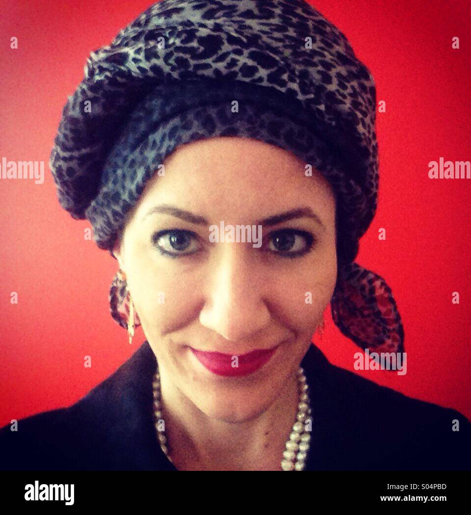 Woman wearing head scarf against red wall Stock Photo