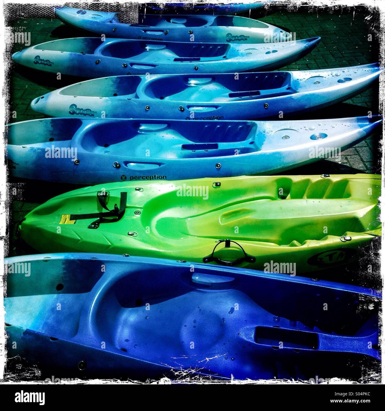 Blue and yellow kayaks on the shoreline. Hipstamatic jagged edge photo. Saturated colours. Stock Photo