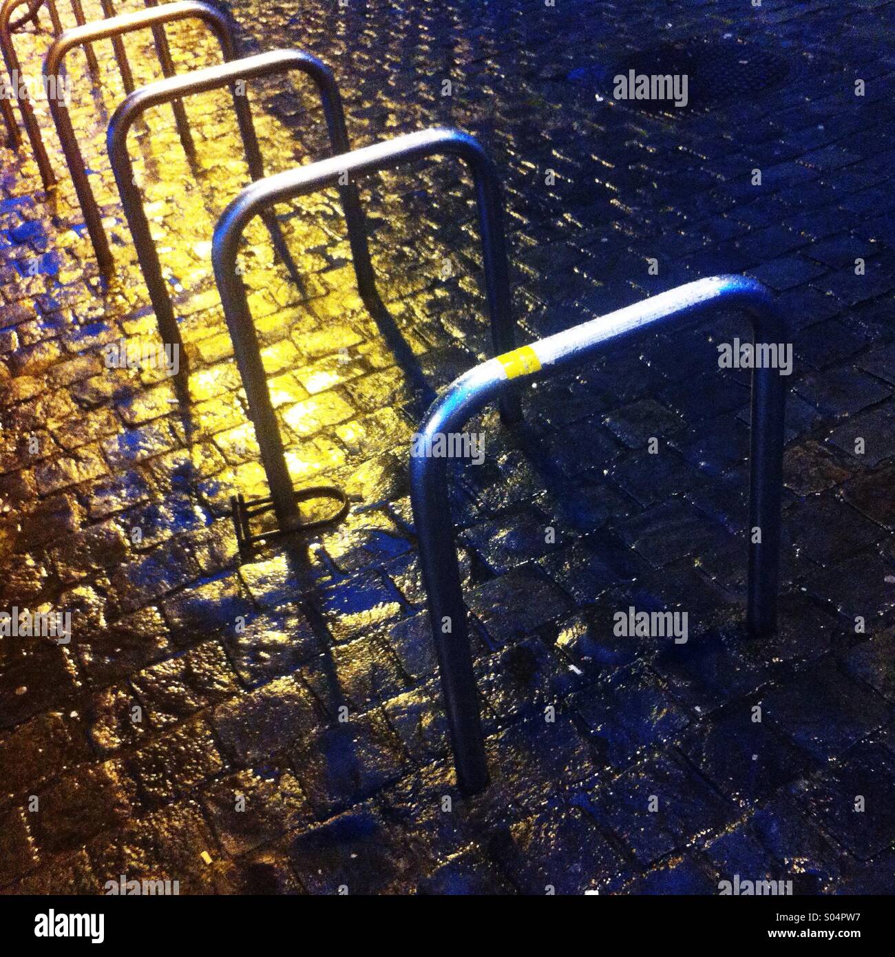 Bicycle rack on the yellow lit cobblestone in Brussels, Belgium, 2014. - Smartphone Captured Stock Image