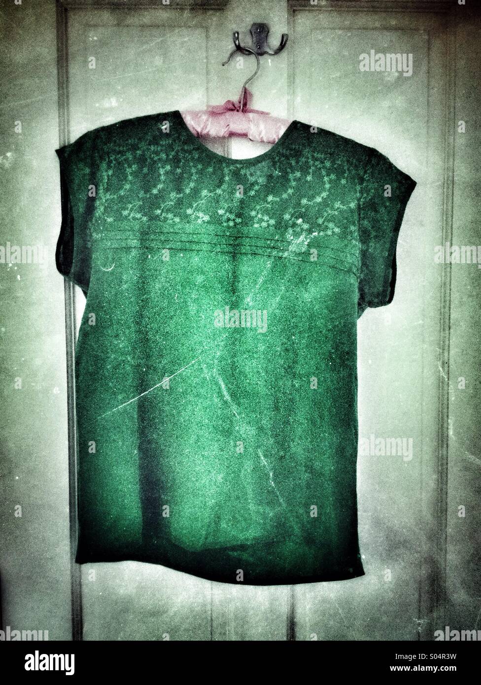 Green silk ladies sleeveless shirt on a hanger on the bathroom door - Smartphone Captured Stock Image