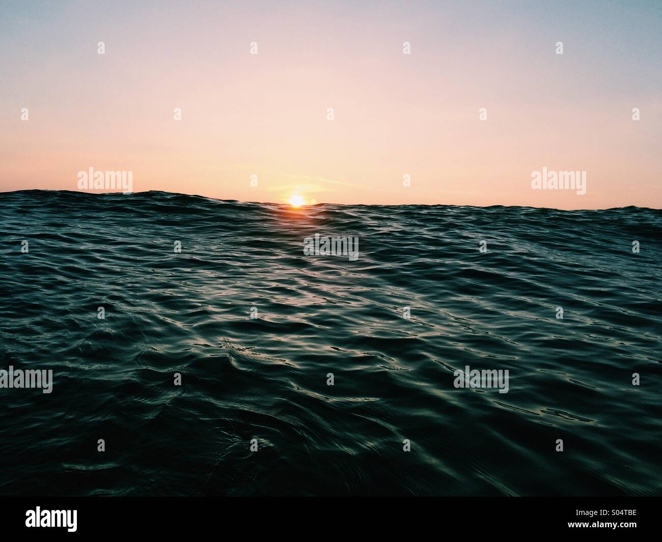 Sunset over an approaching wave in summer Stock Photo