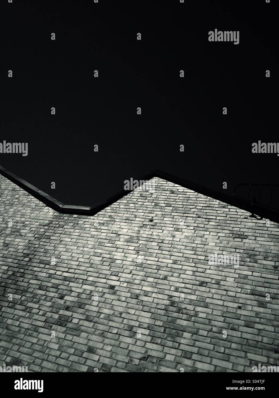 Brick wall and roof against dark sky. - Smartphone Captured Stock Image
