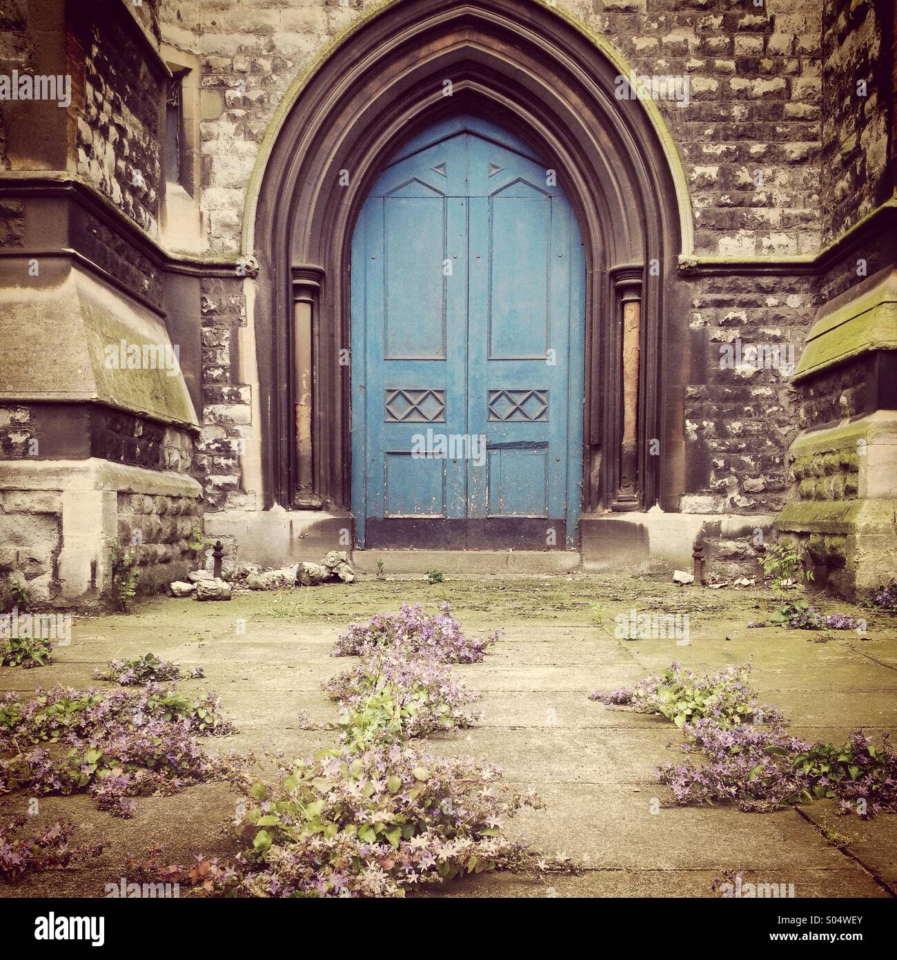 Blue Church Door With Purple Flowers On The Path Stock Photo