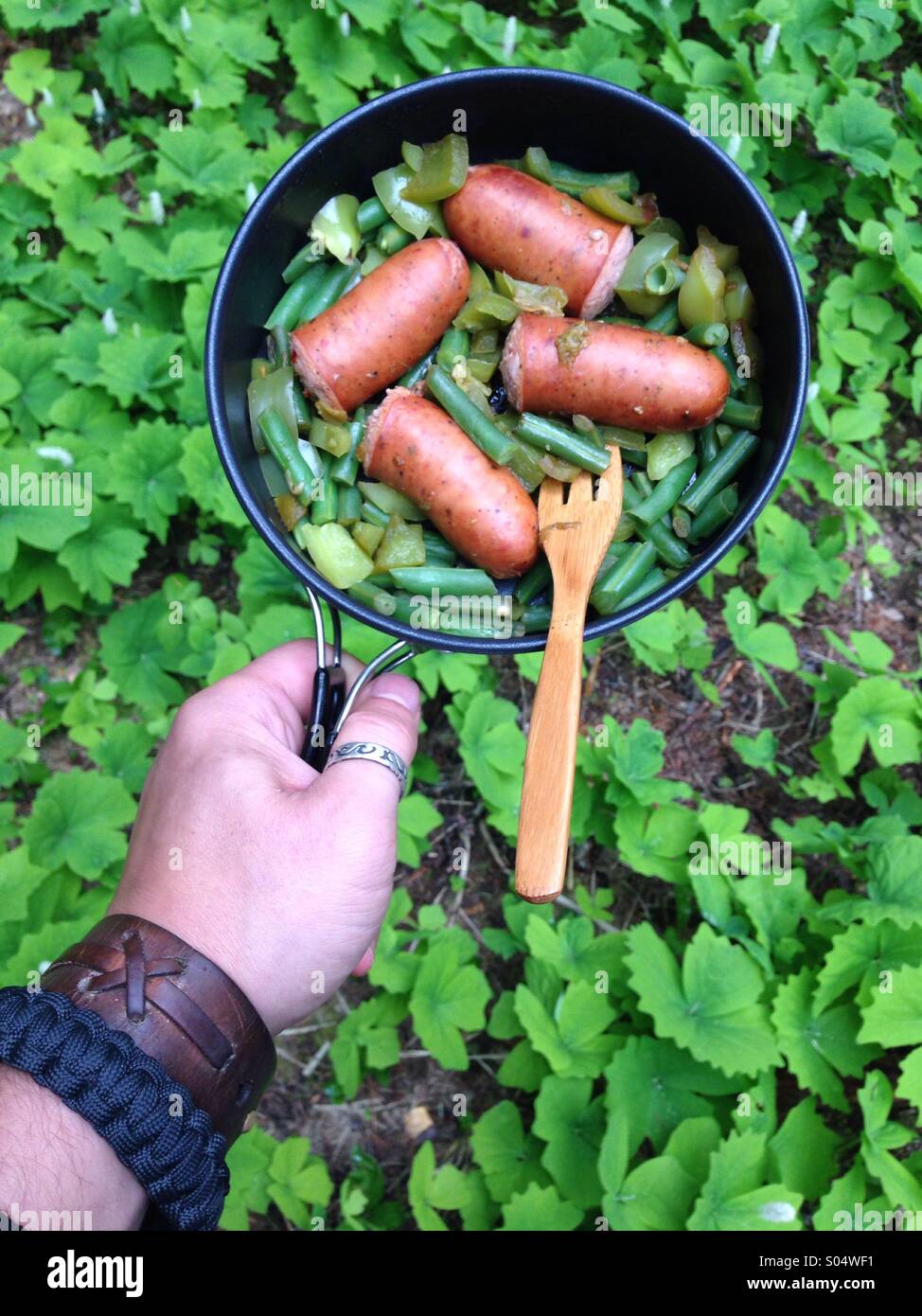 Camp food : Italian sausages and green beans with wild forest greens. Stock Photo