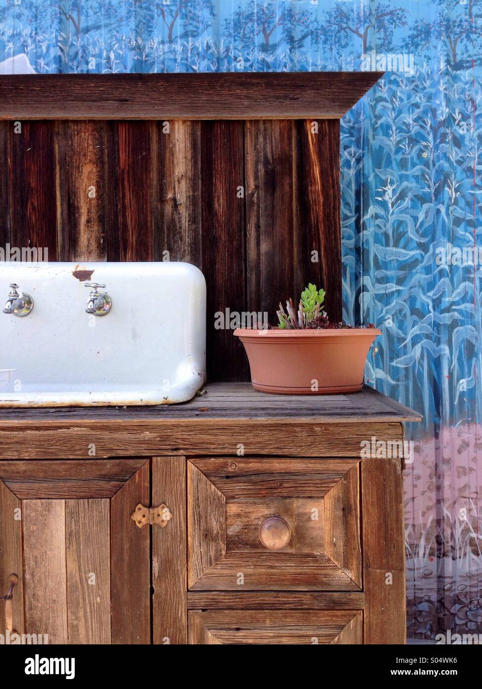 Old wooden cabinet and sink used outdoors for potting plants. - Smartphone Captured Stock Image Old wooden cabinet and sink used outdoors for potting plants. - Smartphone Captured Stock Image