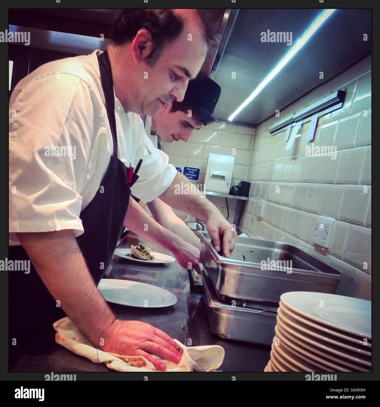 Chefs prepare food in a commercial kitchen. Instagram style iPhone mobile phone photo. - Smartphone Captured Stock Image