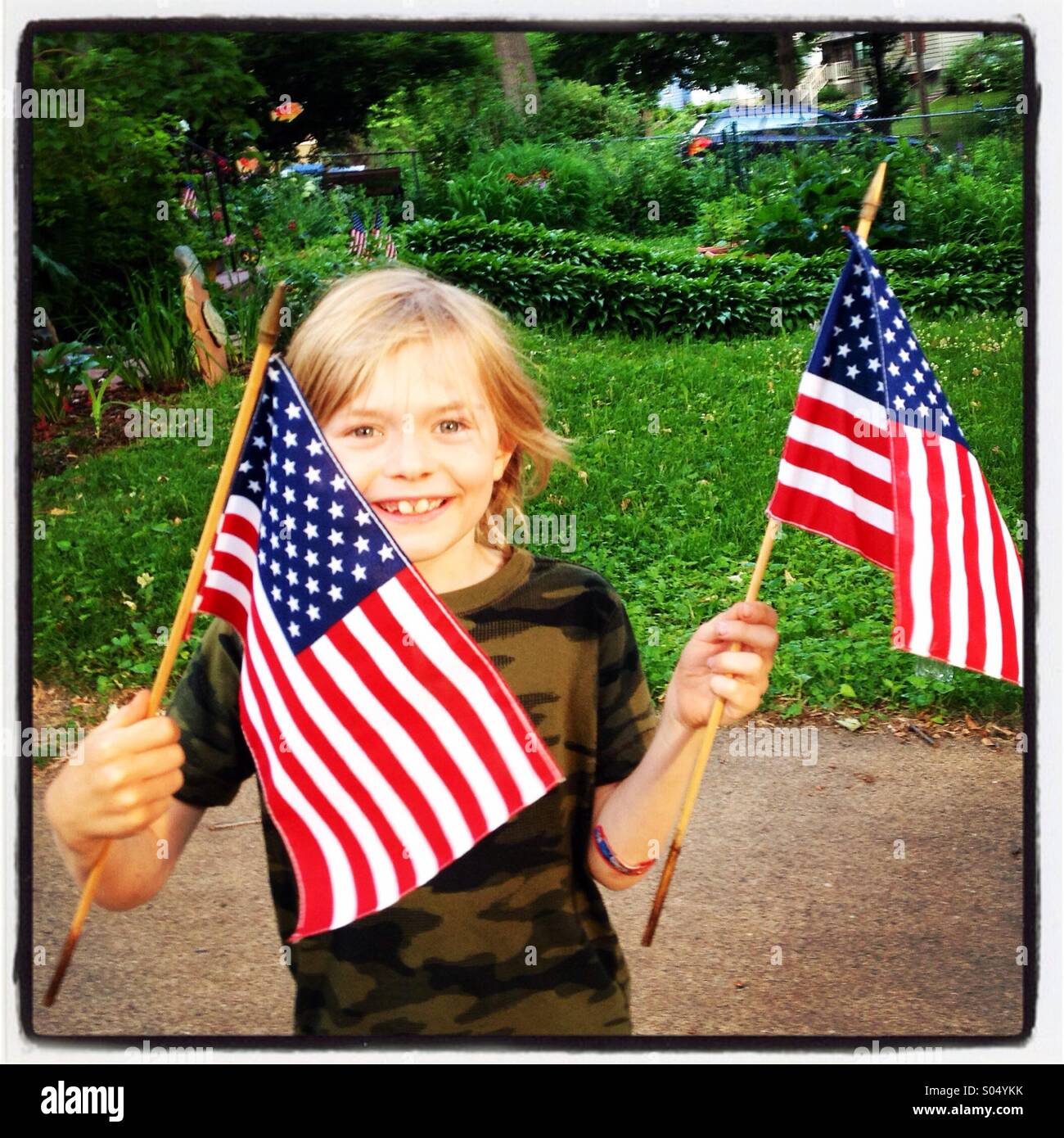 7 year old boy waves flags on July 4th. Stock Photo