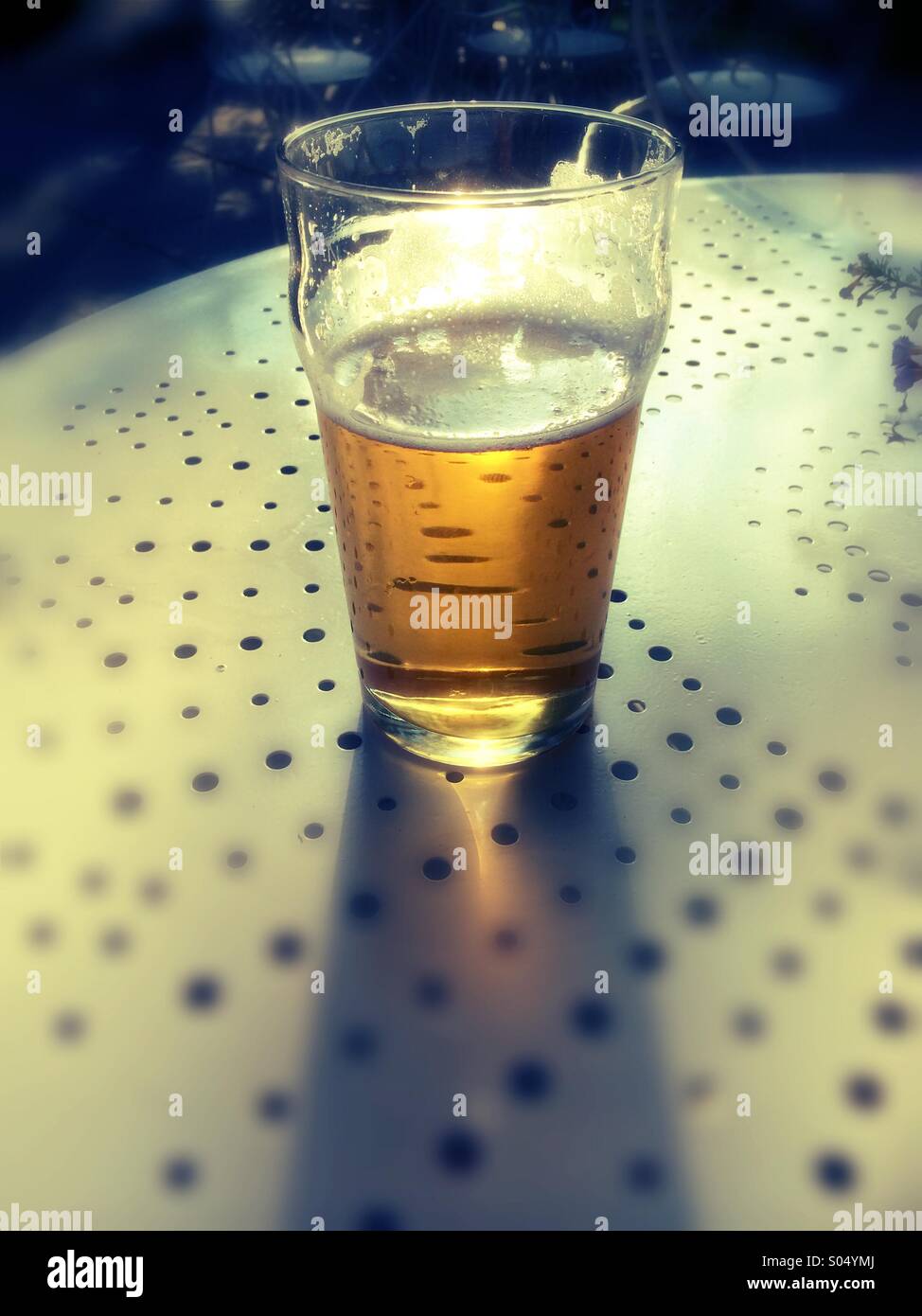 A pint of beer on table with strong backlit and sun flare - Smartphone Captured Stock Image