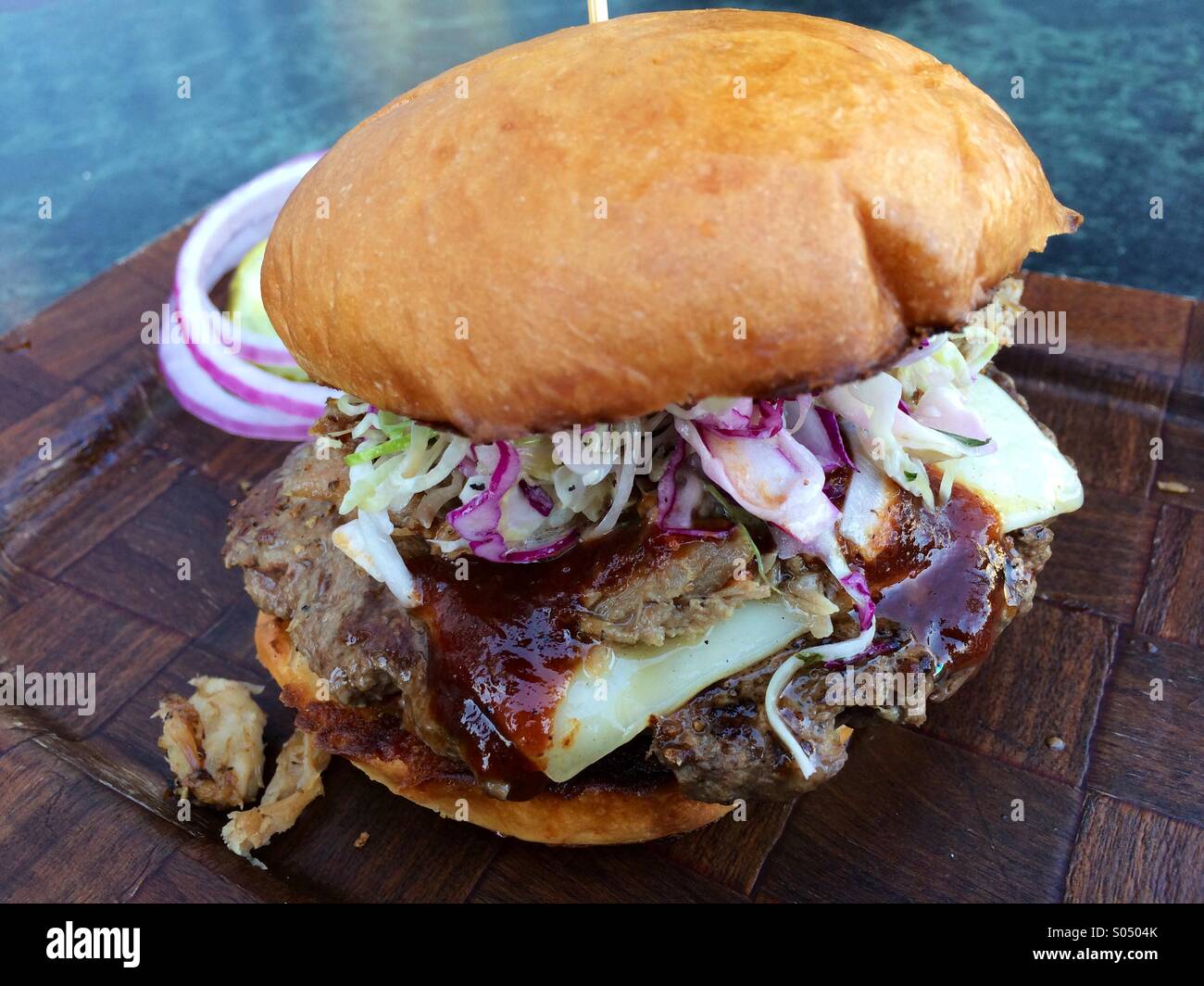 BBQ white cheddar burger with pulled pork, cabbage slaw, & crispy potatoes Stock Photo