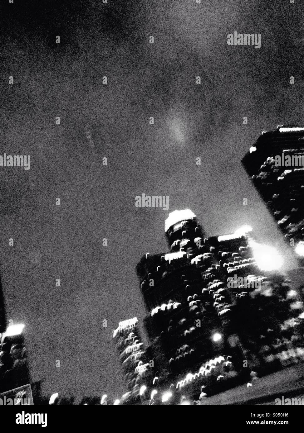 Black-and-white photo of tall buildings in downtown Los Angeles shot from a moving car at night. Stock Photo