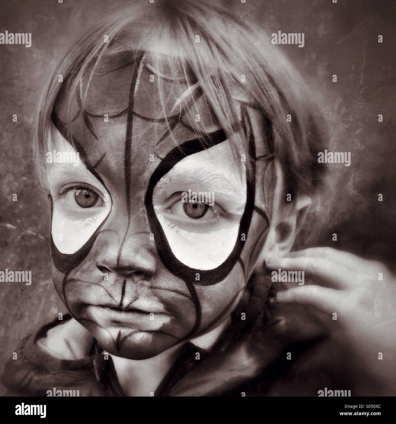 Sad Spidey. Boy unhappy in Spider-Man face makeup Stock Photo