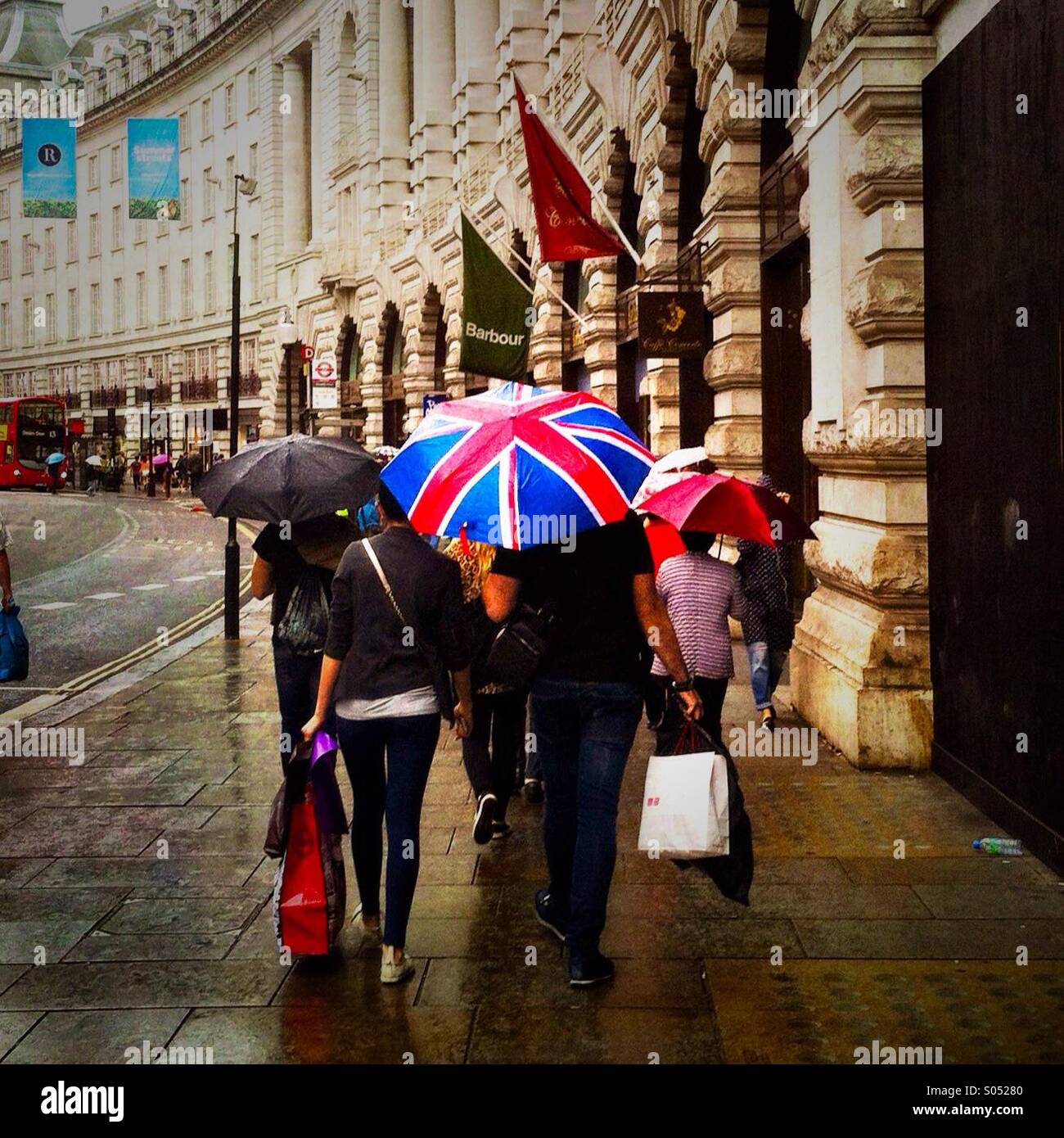 People with a Britain flag color umbrella walk down Regent street on a rainy day. London England UK. - Smartphone Captured Stock Image
