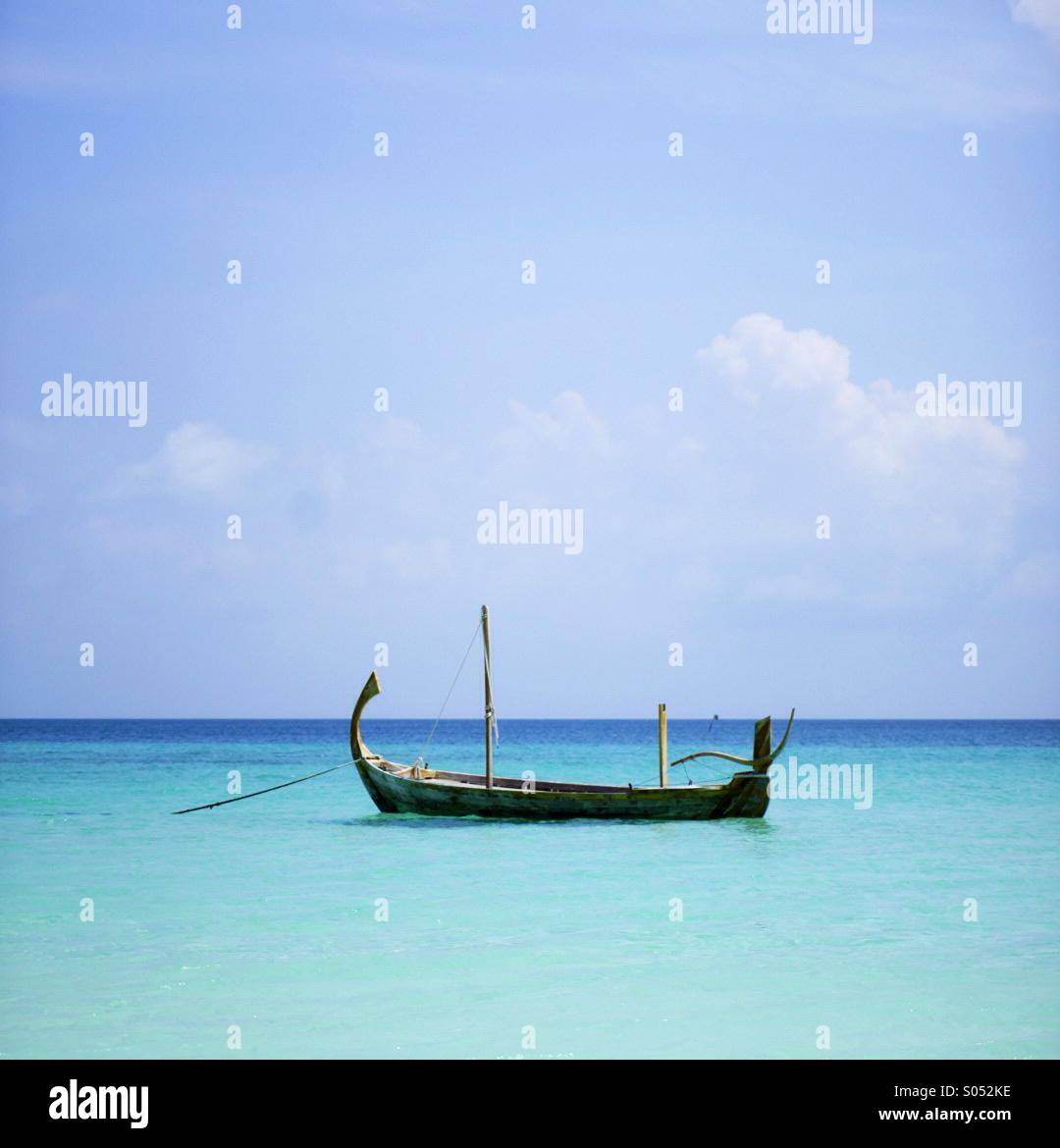 Traditional boat floats on the tranquil turquoise blue ocean off the