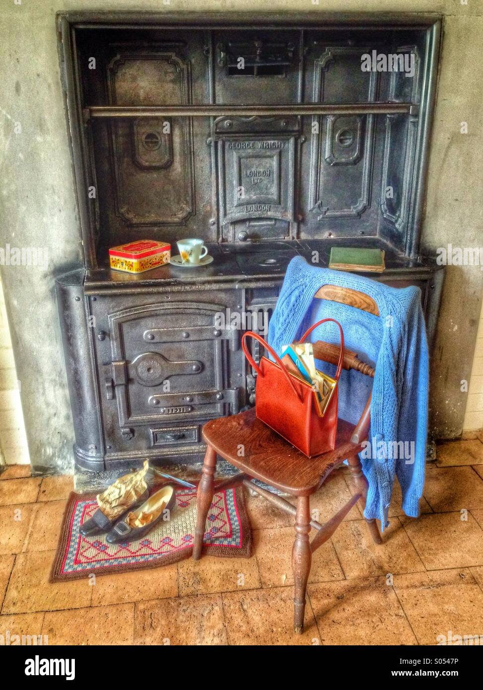 A wooden chair with a cardigan by a kitchen cabinet - Smartphone Captured Stock Image
